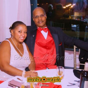 Smiling couple seated at dinner table.